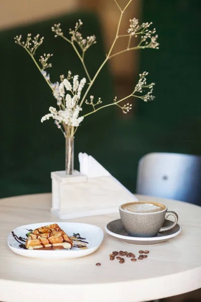 Secangkir kopi dan sepiring wafel belgian di meja kayu ringan — Stok Foto