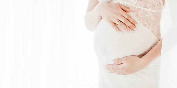 Nahaufnahme einer schwangeren Frau, die ihren Bauch mit den Händen berührt. — Stockfoto