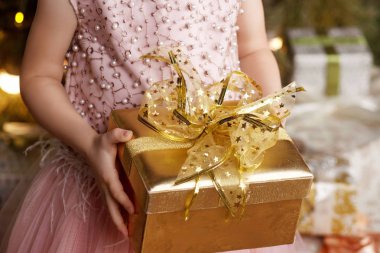 Altın hediye kutusunu tutan çocuk elleri. Christma ile küçük kız
