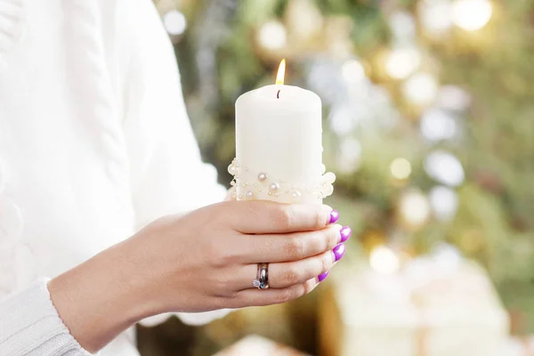 Burning candle in the hands of a girl. Christmas candle. Christm