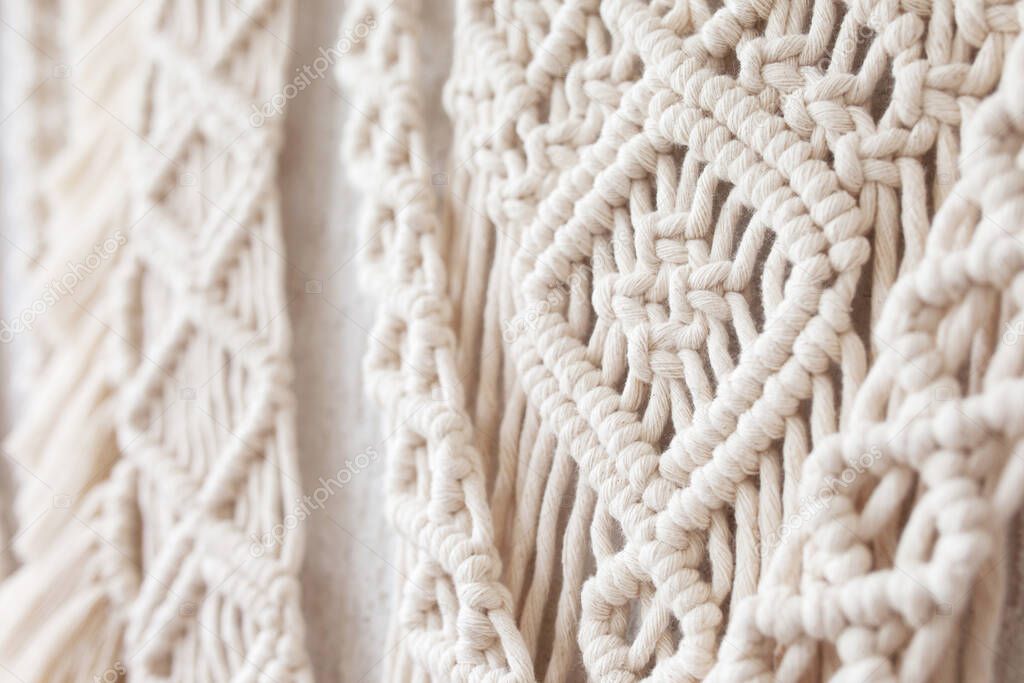Close-up of hand made macrame texture pattern.  ECO friendly modern knitting DIY natural decoration concept  in the interior. Flat lay. Handmade macrame 100% cotton. Details close up. Female hobby. 