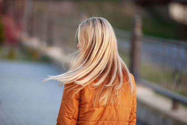Pretty woman with long hair on the street at sunset. Back view. Fashion outdoor photo of beautiful  flying blonde  hair. Close up picture