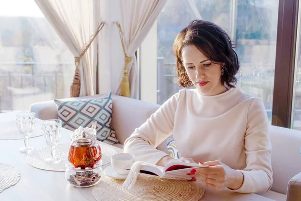 居心地の良いカフェで本を読む美しい女性 ビジネスマンの女性はお茶と一休みします おしゃれなカフェでの明るいライフスタイル写真 — ストック写真