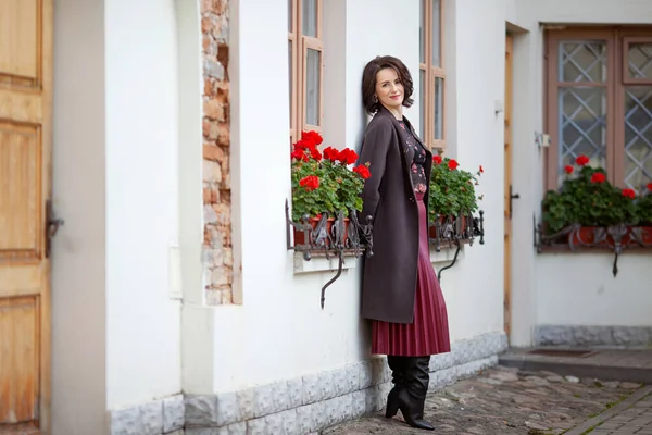 晴れた秋や春の日に通りの壁の近くに滞在する美しい笑顔の女性の中年 茶色のコートを着たモデル — ストック写真