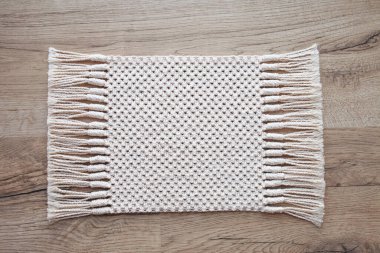 Ahşap masada Macrame kilim ya da yerde halı. El yapımı bej renkli makrome desenli arka plan. Makrame dokusu, ECO dostu, modern örgü.. 