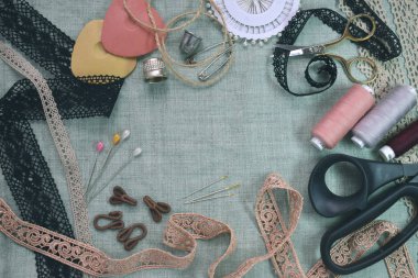 Dikiş sahnesi masa düz kompozisyon yatıyordu. İplik, dantel, iğne, makas, teyp, makara, bez. Pastel renkler keten kumaş metin alanı. Üst görünüm Banner şablonu