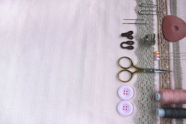 Sewing scene table flat lay side composition. Threads, lace, pins, scissors, tape, reel, cloth. Pastel colors linen fabric text space. Top view banner template