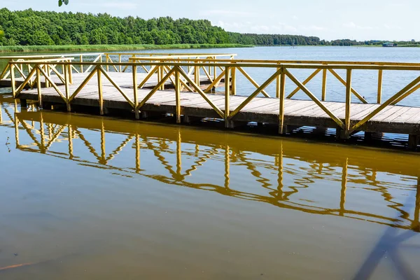 Wooden flooring with railings is reflected in the water of a small lake