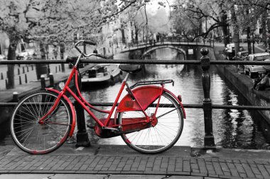 Yalnız kırmızı bisiklet Amsterdam kanal üzerinde köprü üzerinde bir resim. Arka plan siyah ve beyaz olduğunu. 