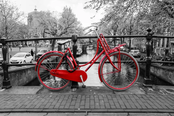Yalnız kırmızı bisiklet Amsterdam kanal üzerinde köprü üzerinde bir resim. Arka plan siyah ve beyaz olduğunu. 