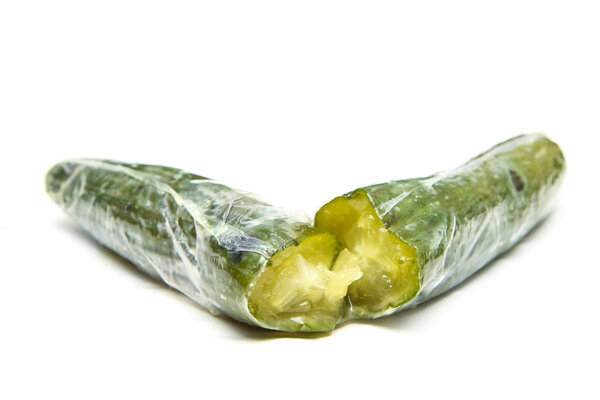 A picture of a rotten cucumber packed in the plastic foil. The foil is useless, it only damages the vegetable and it only goes mouldy. Isolated on a white background. 