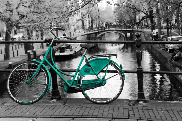 阿姆斯特丹海峡上的桥上一张孤独的蔚蓝自行车的照片 背景是黑白的 — 图库照片