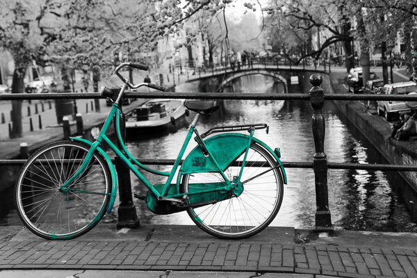 Фото одинокого лазурного велосипеда на мосту через канал в Амстердаме. Фон чёрный и белый
. 