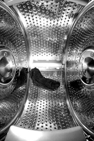 A look inside the perforated steel drum of the empty washing machine. Only one sock is left there.