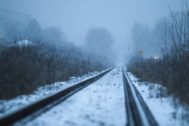 Demiryolunun kasvetli bir görüntüsü. Kar yağışı devam ediyor ve raylı mesafe gider ve görüş dışına gidiyor. 