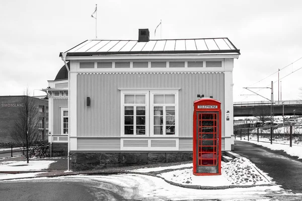A traditional red British phone box standing by the traditional wooden cottage in Sweden. Unusual couple of country symbols.