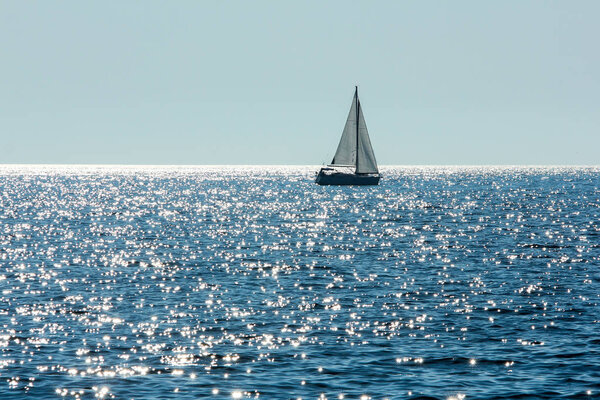 A picture of a lonely boat floating on the blue ocean during the hot summer day. Relaxing vacation activity for the people. 