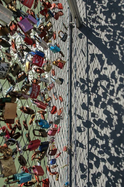 The love locks are hanging on a fence on a bridge. It is some kind of vandalism and problm for the local government.