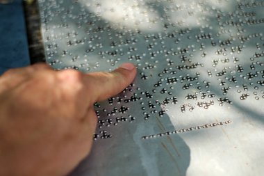 Braille alfabesindeki metnin bir ayrıntısı. Bir bilgi işaretinin ayrıntıları. Parmak şu anda okuyor.. 