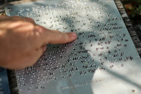 Braille alfabesindeki metnin bir ayrıntısı. Bir bilgi işaretinin ayrıntıları. Parmak şu anda okuyor.. 