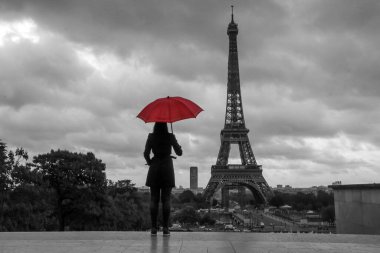 Kırmızı şemsiyeli bayan Fransa 'da Paris' te Eyfel kulesinin önünde duruyor. İzole edilmiş kırmızı şemsiyeli siyah beyaz resim.