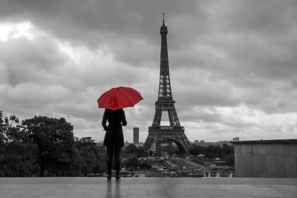 Kırmızı şemsiyeli bayan Fransa 'da Paris' te Eyfel kulesinin önünde duruyor. İzole edilmiş kırmızı şemsiyeli siyah beyaz resim.