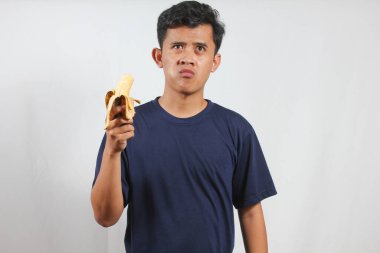 Muz yiyen genç Asyalı adam izole edilmiş beyaz arka plan