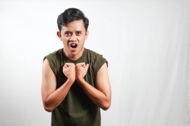 Heyecanlı genç Asyalı adam beyaz arka planda izole edilmiş kol kaslarını gösteriyor.