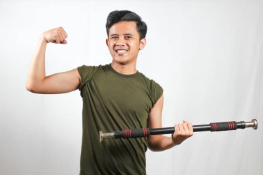 Asyalı adam beyaz arka planda izole edilmiş pazı kaslarını gösterirken hafif halteri kaldırıyor.