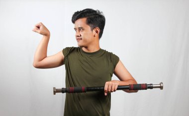 Asyalı adam beyaz arka planda izole edilmiş pazı kaslarını gösterirken hafif halteri kaldırıyor.