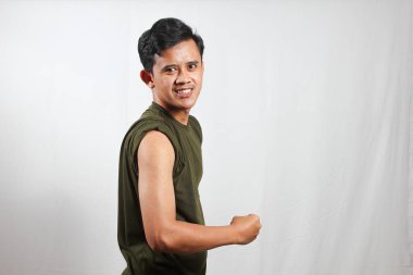 Heyecanlı genç Asyalı adam beyaz arka planda izole edilmiş kol kaslarını gösteriyor.