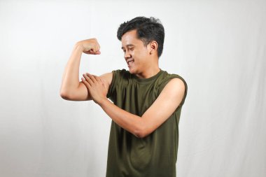 Kendine güvenen genç bir adam gülümseyerek kaslarını esnetiyor, yaşam tarzı içeriği için zindelik ve sağlık gösteriyor.