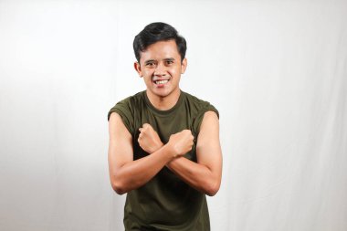 Kendine güvenen genç bir adam gülümseyerek kaslarını esnetiyor, yaşam tarzı içeriği için zindelik ve sağlık gösteriyor.