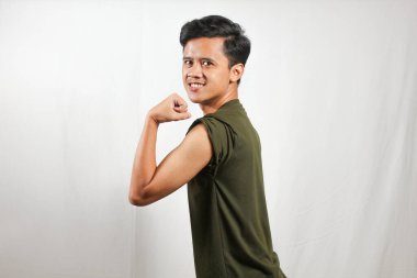 Kendine güvenen genç bir adam gülümseyerek kaslarını esnetiyor, yaşam tarzı içeriği için zindelik ve sağlık gösteriyor.