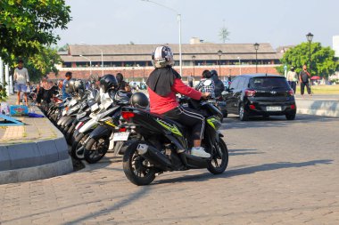 Endonezya, Solo - 21 Eylül 2025: Asfaltlı yolda motosiklet süren genç bir kadın