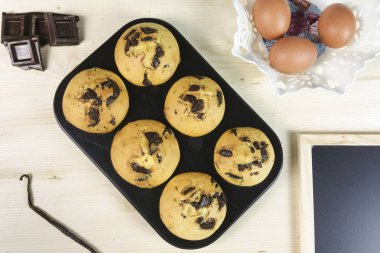 Kek çikolata damla çörek tepsisi, yumurta ve vanilya çekirdeği üzerinde ahşap arka plan - üstten görünüm