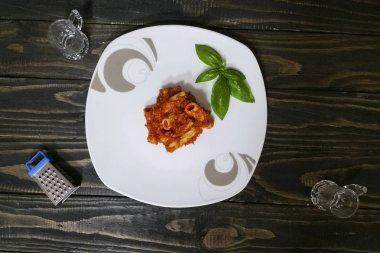 Makarna salça ve ahşap arka plan - üstten görünüm üzerinde beyaz tabakta fesleğen ile