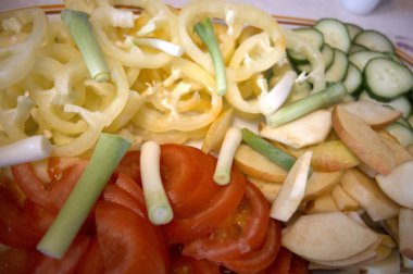 Taze kesilmiş sebzeler arasında domates, salatalık, kırmızı biber ve taze soğan var..