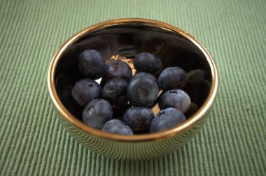 Fotokopi alanı olan altın bir kasede taze yaban mersinlerinin yakın plan çekimi..