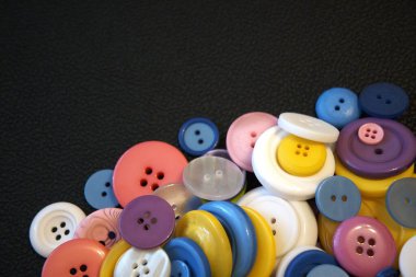 Siyah deri arka plana yerleştirilmiş farklı renklerdeki düğmeler kopyalanır.