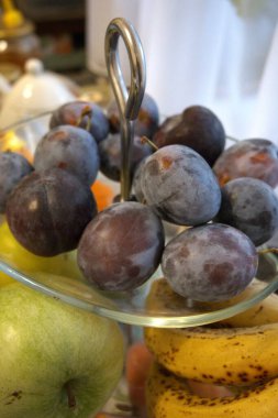 Şeffaf cam servis kâsesine yerleştirilmiş taze eriklerin yakın çekimi. Sağlıklı meyve kavramı.