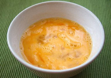 Yeşil arka planı olan bir kasede taze yumurta karışımı. Yakın çekim..