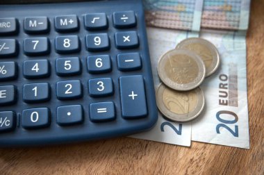 Tasarruf, fatura, gider, gelir, enflasyon ve ekonomiyi temsil eden bir hesap makinesinin yanına yerleştirilen avro para birimi banknotları.