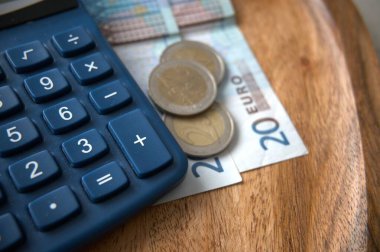 Tasarruf, fatura, gider, gelir, enflasyon ve ekonomiyi temsil eden bir hesap makinesinin yanına yerleştirilen avro para birimi banknotları.