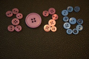 Katı siyah arkaplandaki renkli düğmelerden düzenlenmiş 2026 sayısının yaratıcı bileşimi. Kopyalama alanı olan en küçük konsept.