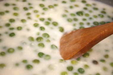 Geleneksel ev yapımı yeşil bezelye güveci tencerede pişiyor..