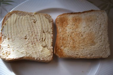Bir tabakta iki dilim tost, biri margarinli ve biri sade, sembolik seçim, kahvaltı, diyet..