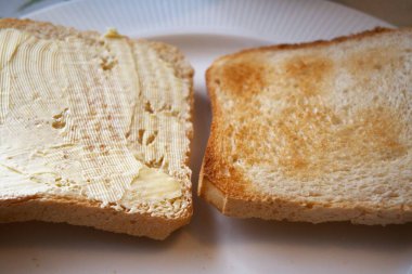 Bir tabakta iki dilim tost, biri margarinli ve biri sade, sembolik seçim, kahvaltı, diyet..
