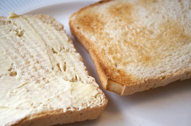 Bir tabakta iki dilim tost, biri margarinli ve biri sade, sembolik seçim, kahvaltı, diyet..