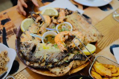 Portekiz usulü ızgara deniz ürünleri tabağında karides sardalya limon dilimleri patates kızartması salata ekmeği düzleşmiş köy restoranı aile yemeği vardı. Yüksek kalite fotoğraf